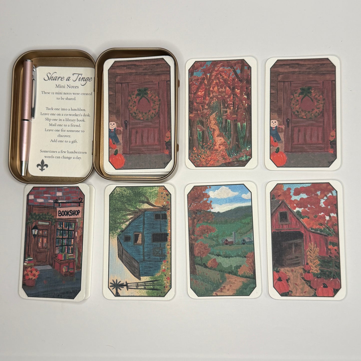 Rose gold Mini Notes tin with twelve folded cards spread beside it, featuring six original autumn illustrations, plus a coordinating mini pen.
