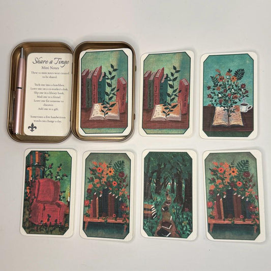 Where Stories Bloom Mini Notes Gift Tin with twelve folded note cards featuring six original bookish and floral illustrations, displayed with a rose gold tin and coordinating mini pen.